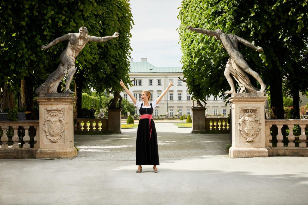 Nachstellung von Julie Andrews in Sound of Music vor der Kulisse des Mirabellgartens in Salzburgs mit dem Schloss Mirabell im Hintergrund